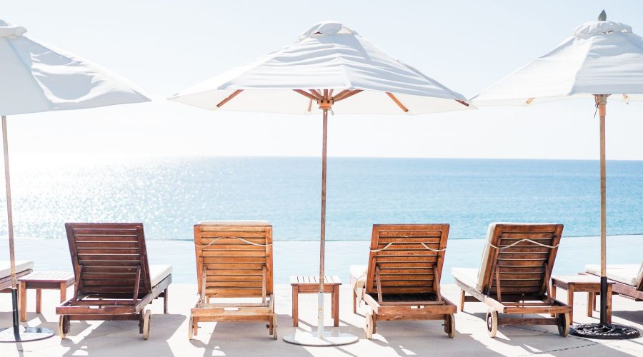 Relaxing beach view with wooden sunloungers and parasols by the ocean. — 3 Top Tailormade Holidaymaker Destinations to go to