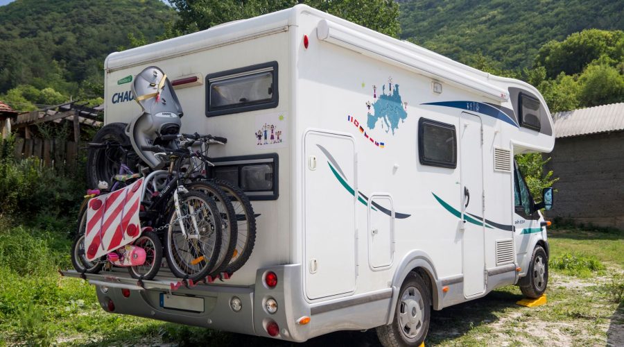 An RV with bicycles attached in a scenic outdoor setting, surrounded by mountains and greenery. — 4 Rules Of Planning The Rig
