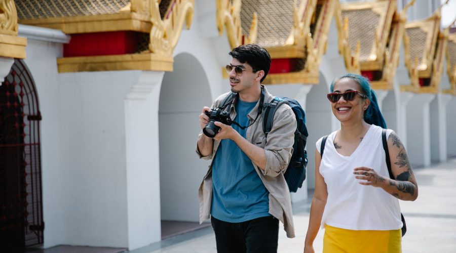 Two tourists with backpacks and cameras enjoy a sunny day exploring ornate Thai architecture. — Adventure Travel Around Austr