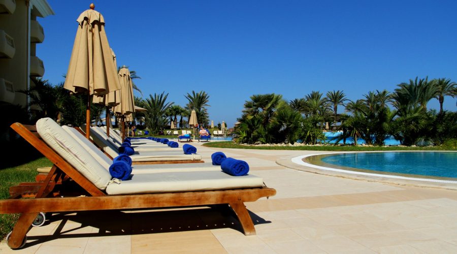 Scenic view of luxurious poolside loungers at a tropical resort under clear blue sky. — Divorced or Divorcing - How you can H