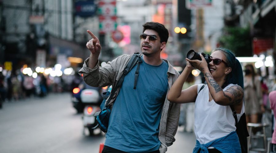 Two tourists capturing street scenes in a busy city, enjoying travel moments. — Flight Attendant Course