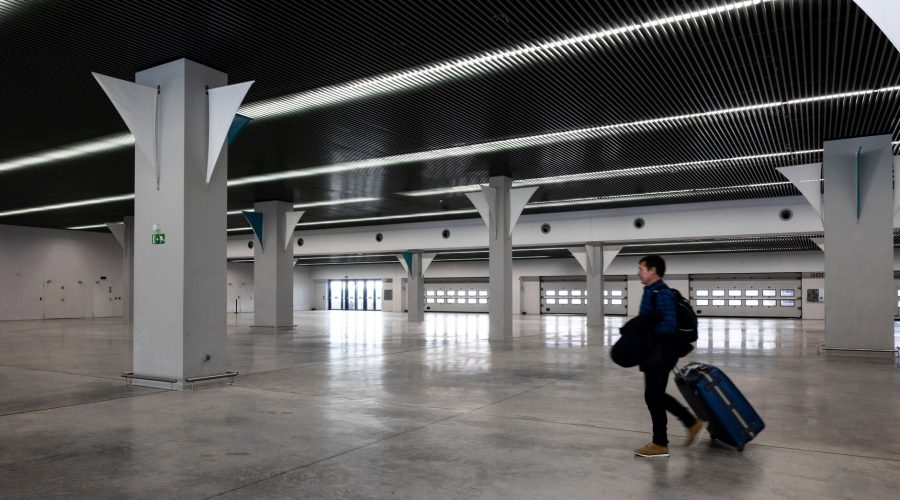 A man with luggage walking through a spacious, modern, empty airport hall. — How to Book a Private Jet for Your Next Trip