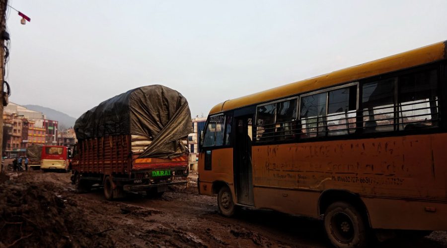 Buses and trucks navigate a muddy urban road, highlighting city travel challenges. — Limousines - Finest Of Transportations