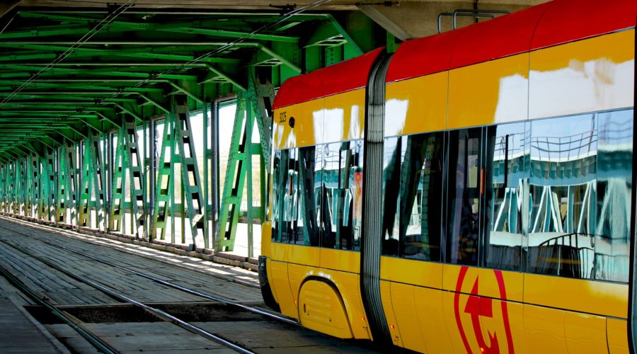 Modern yellow tram traversing an urban green steel bridge, showcasing urban transit infrastructure. — Questions You'll Need S