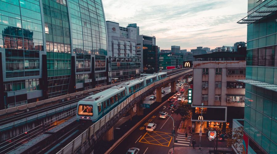 Dynamic cityscape featuring an elevated train amidst modern architecture and busy streets. — The Transportation Inspector Job