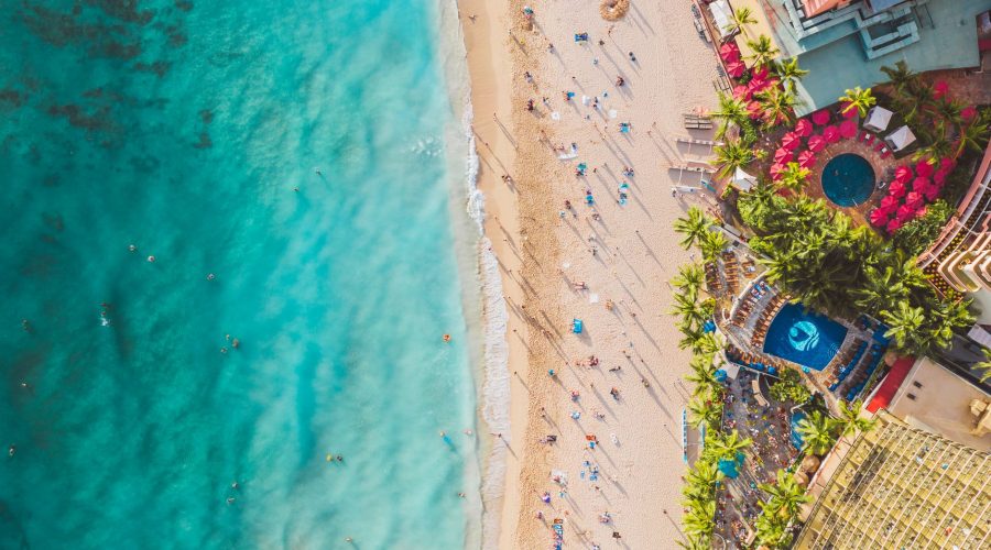Stunning aerial view of a vibrant beach with people, palm trees, and luxury resorts. — Thing to remember Before Booking a vac