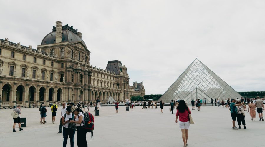 Crowds gather around the iconic Louvre and Pyramid in Paris, showcasing French architecture and culture. — Travel Sites Boost