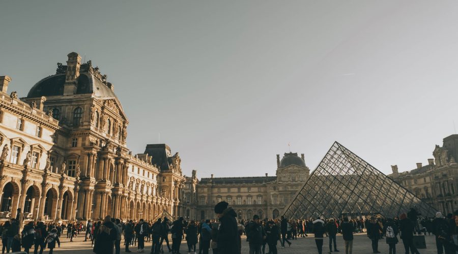 Tourists at the Louvre Museum with the iconic glass pyramid in Paris, France. — What is the best way to meet new people when