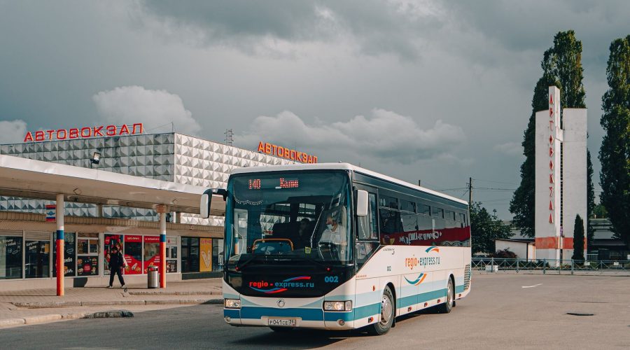 City bus station featuring modern architecture and a parked bus under cloudy skies. — Why Should You Use a Car Cover?