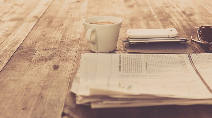 A warm vintage morning setup with coffee, newspaper, and smartphone on wooden table. — Why You Should Spend New Year's Eve in